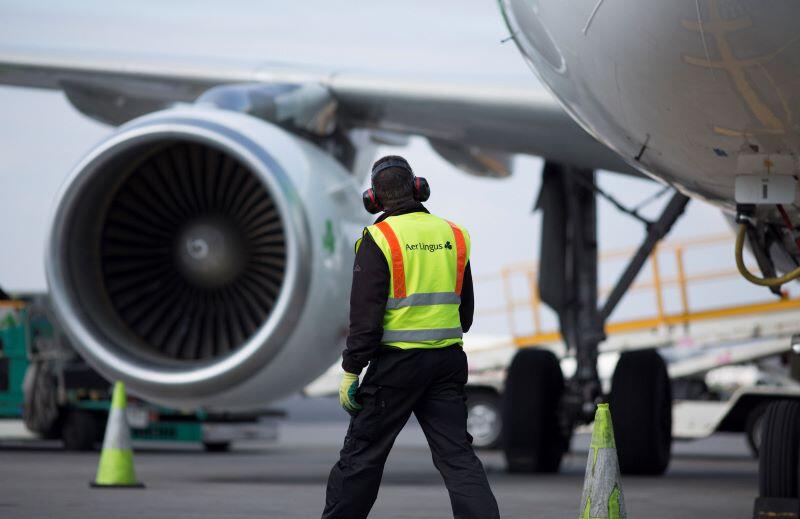 Ground handling staff beside a passenger aircraft and engine