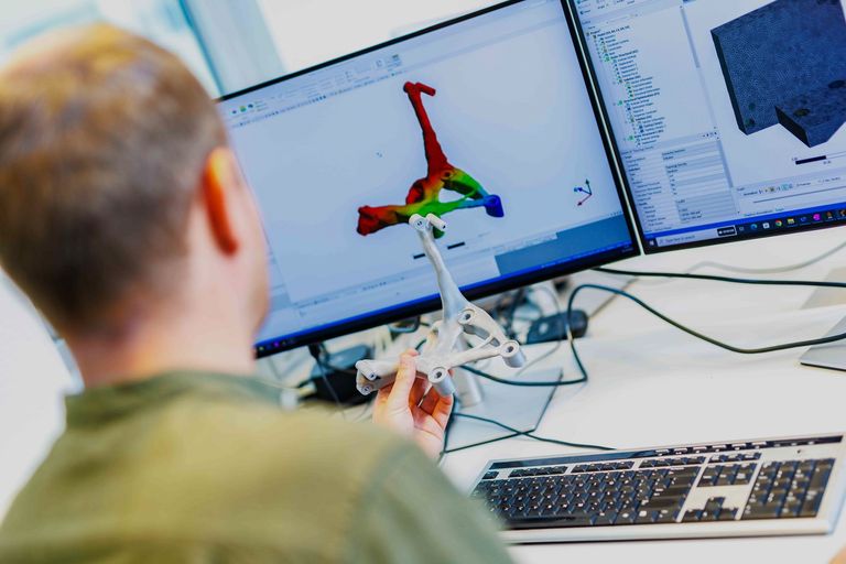 Engineer reviewing a topology-optimised bracket in CAD beside the printed part