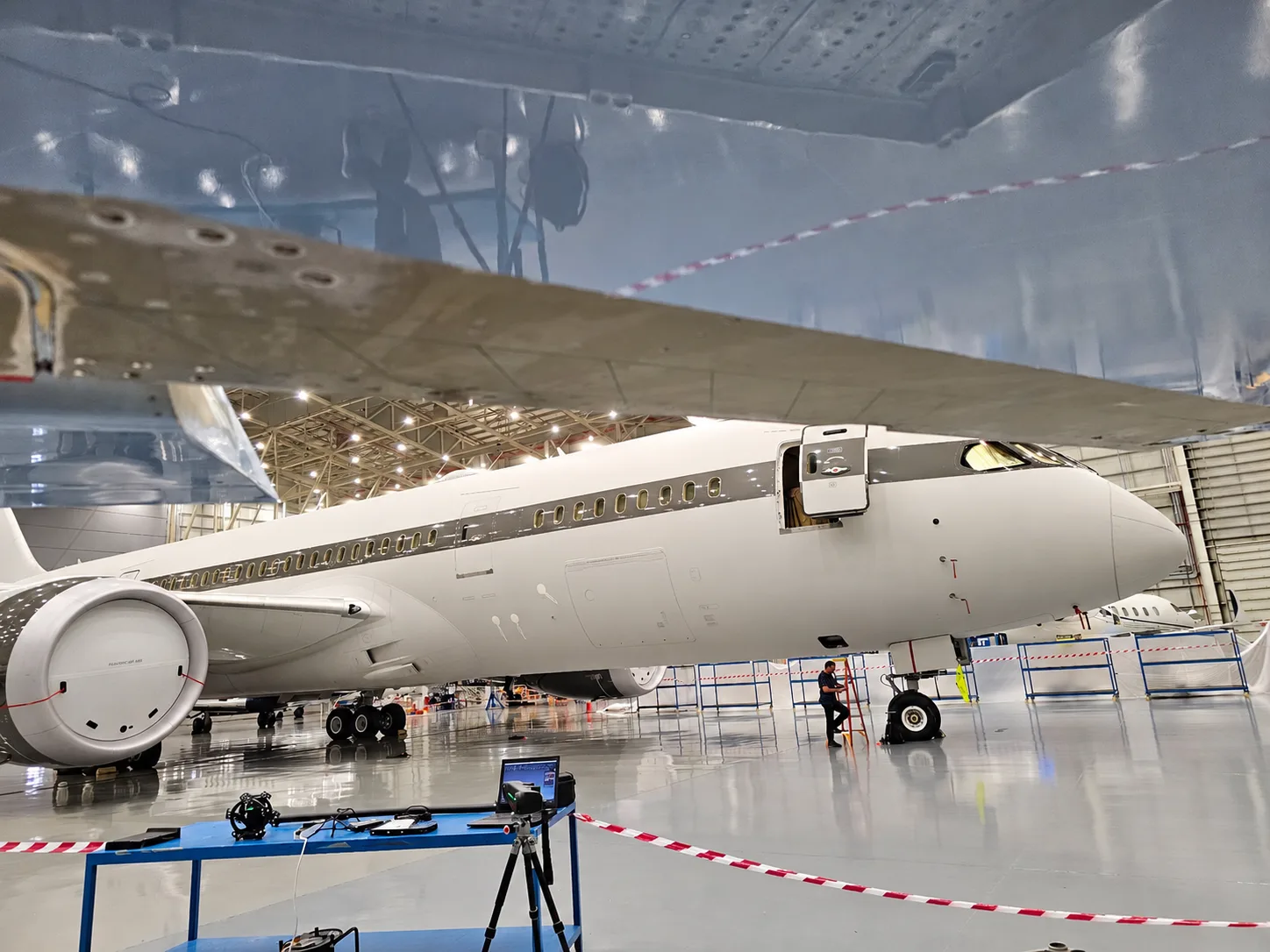 Passenger aircraft in a maintenance hangar viewed from beneath the wing