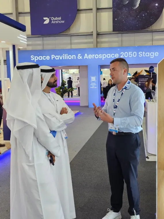 Paradigm 3D representative speaking with visitors in the exhibition aisle at Dubai Airshow 2025