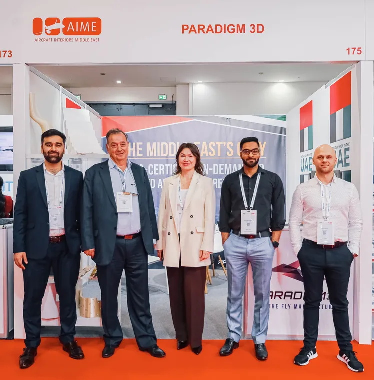 Paradigm 3D team members in front of the stand graphics at MRO Middle East 2025