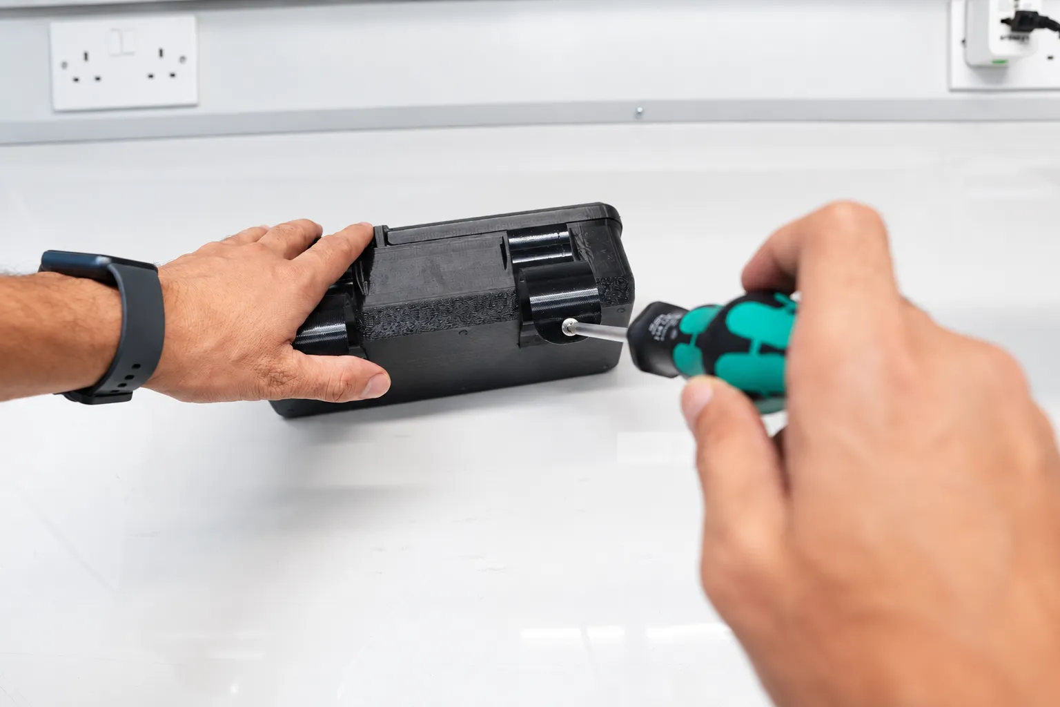 Hands assembling a printed component with a screwdriver