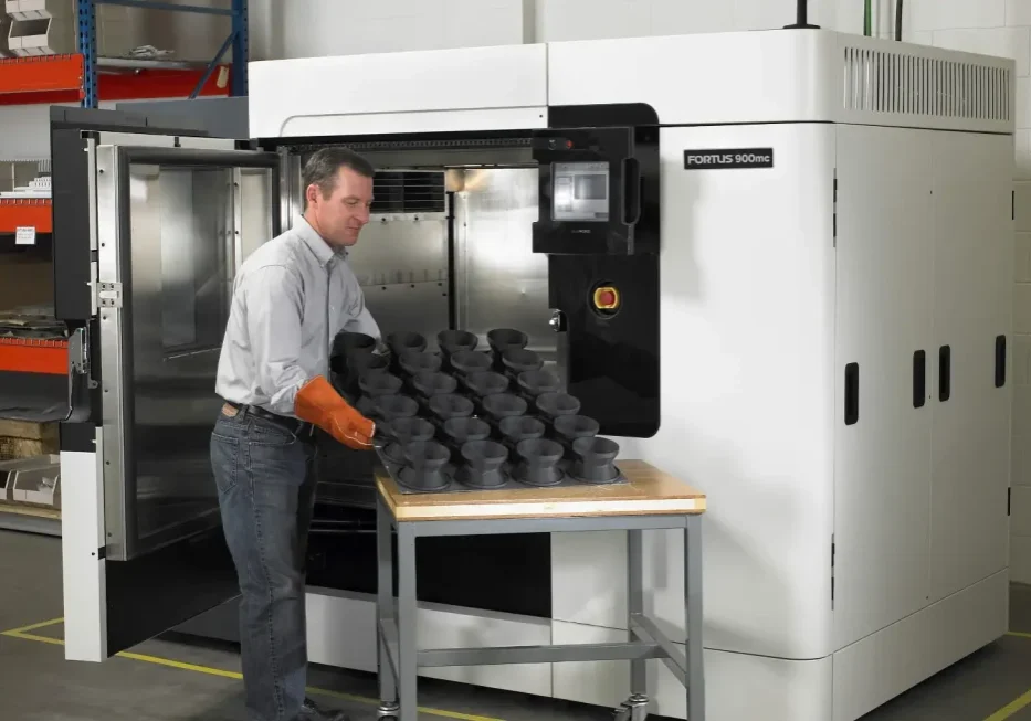 Operator unloading a batch of FDM parts from a Stratasys F900
