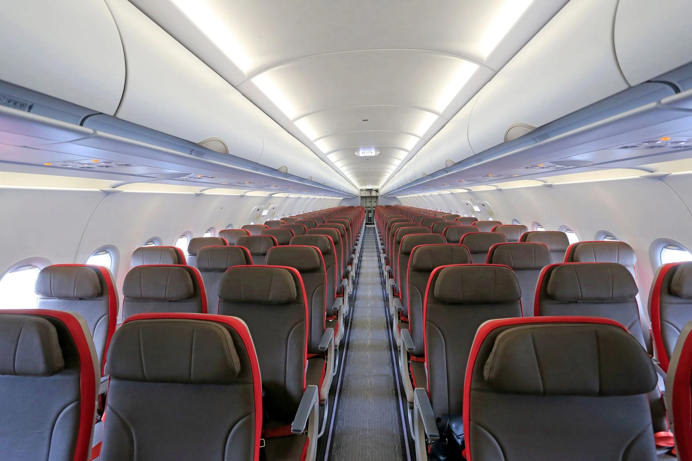 Aircraft cabin interior with rows of red-trimmed passenger seats